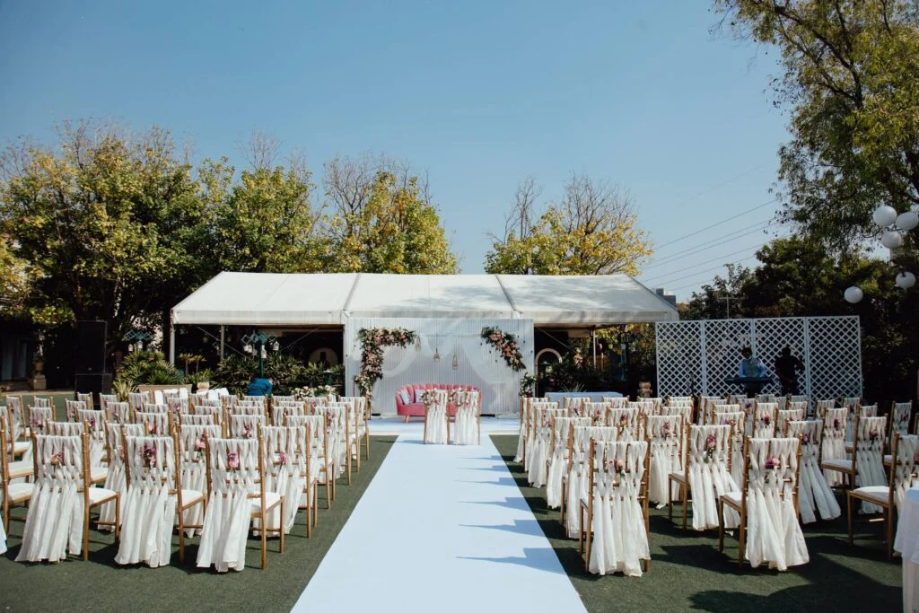White frame tent and ceremony seating set for an outdoor wedding